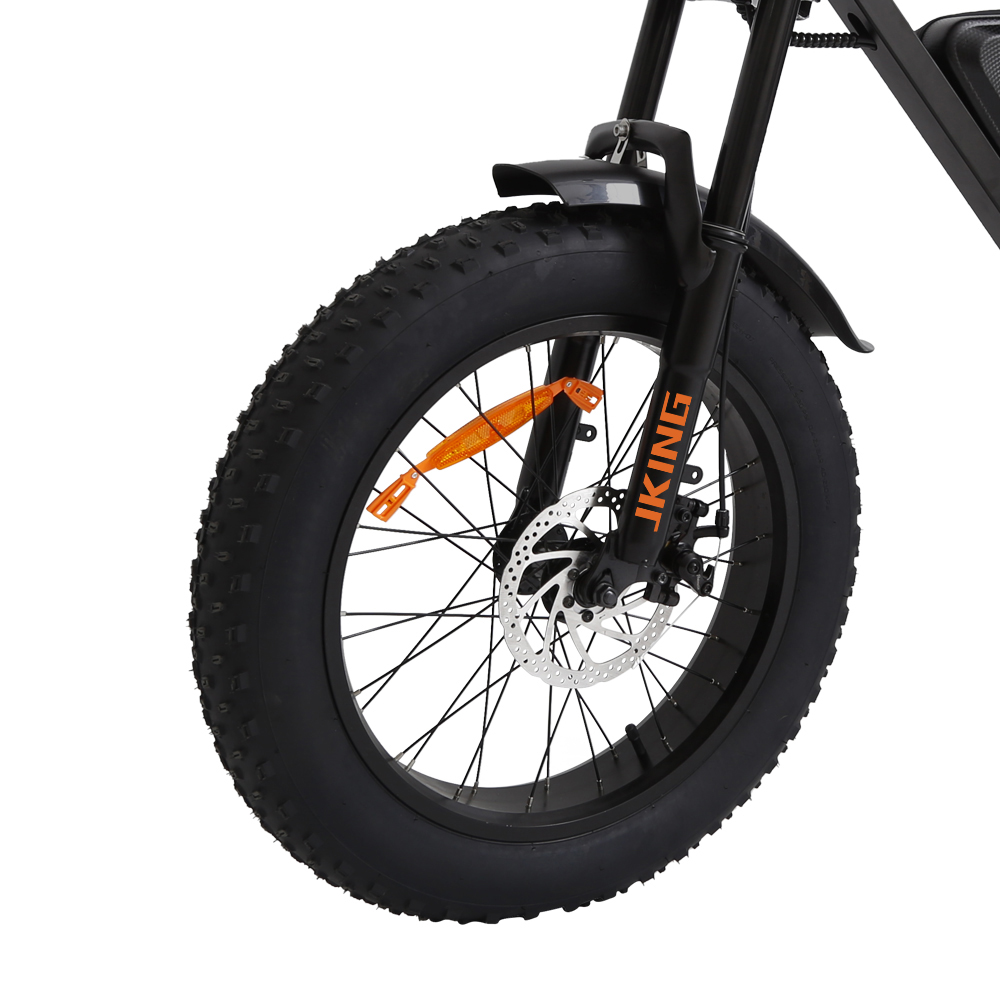 Vorderreifen eines schwarzen Fatbikes mit orangefarbenem Reflektor und Scheibenbremse.