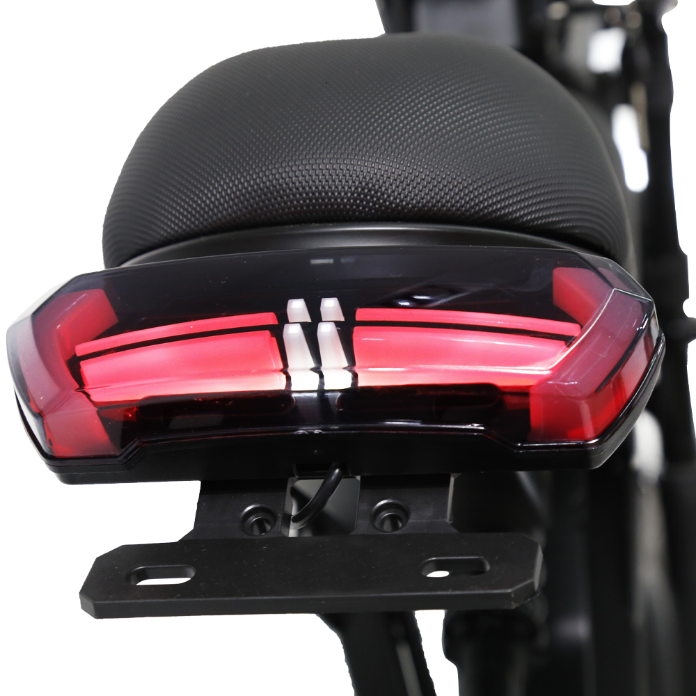 Nahaufnahme des roten LED-Rücklichts und des texturierten schwarzen Sitzes eines Motorrads.