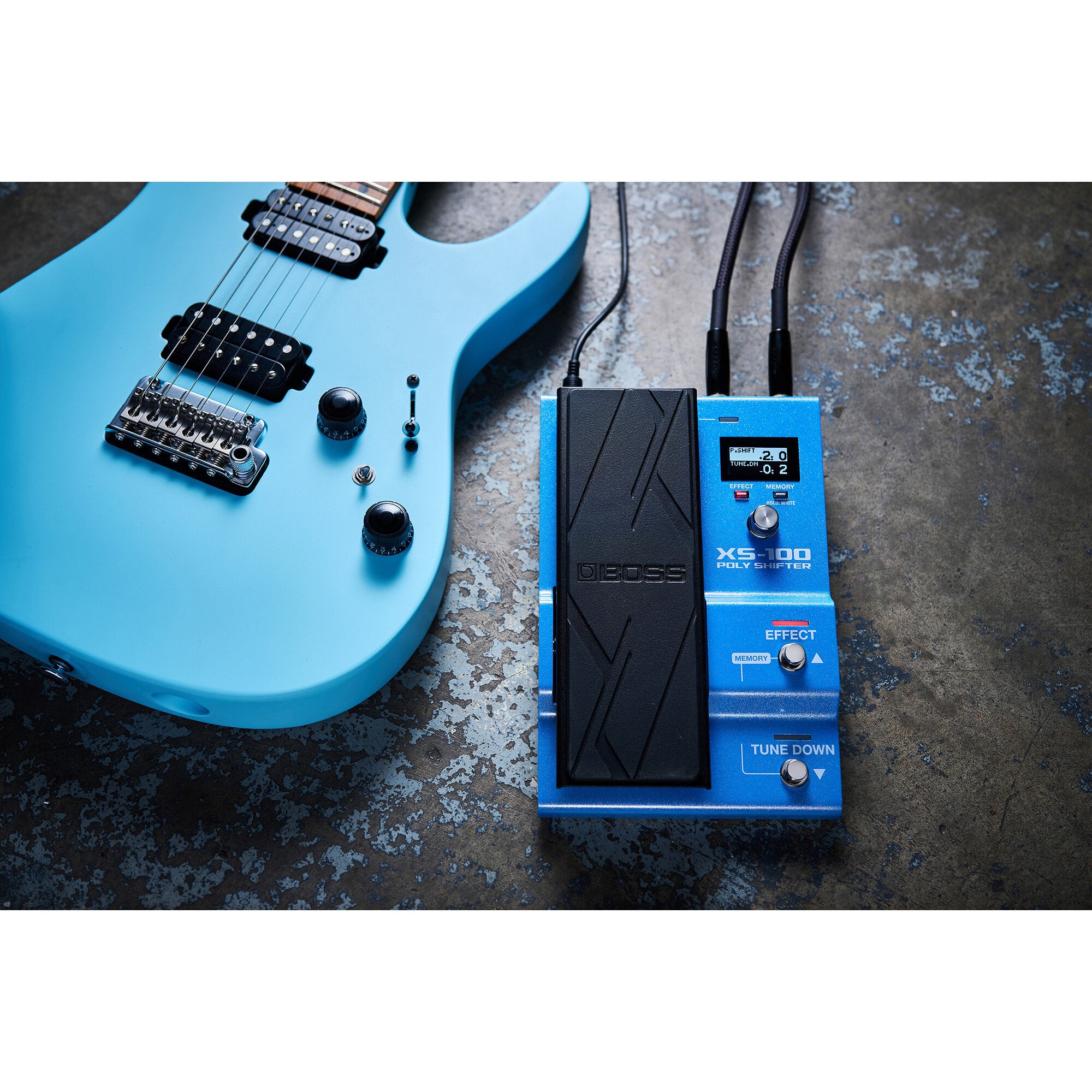 Een lichtblauwe elektrische gitaar en een Boss XS-100 Poly Shifter pedaal.