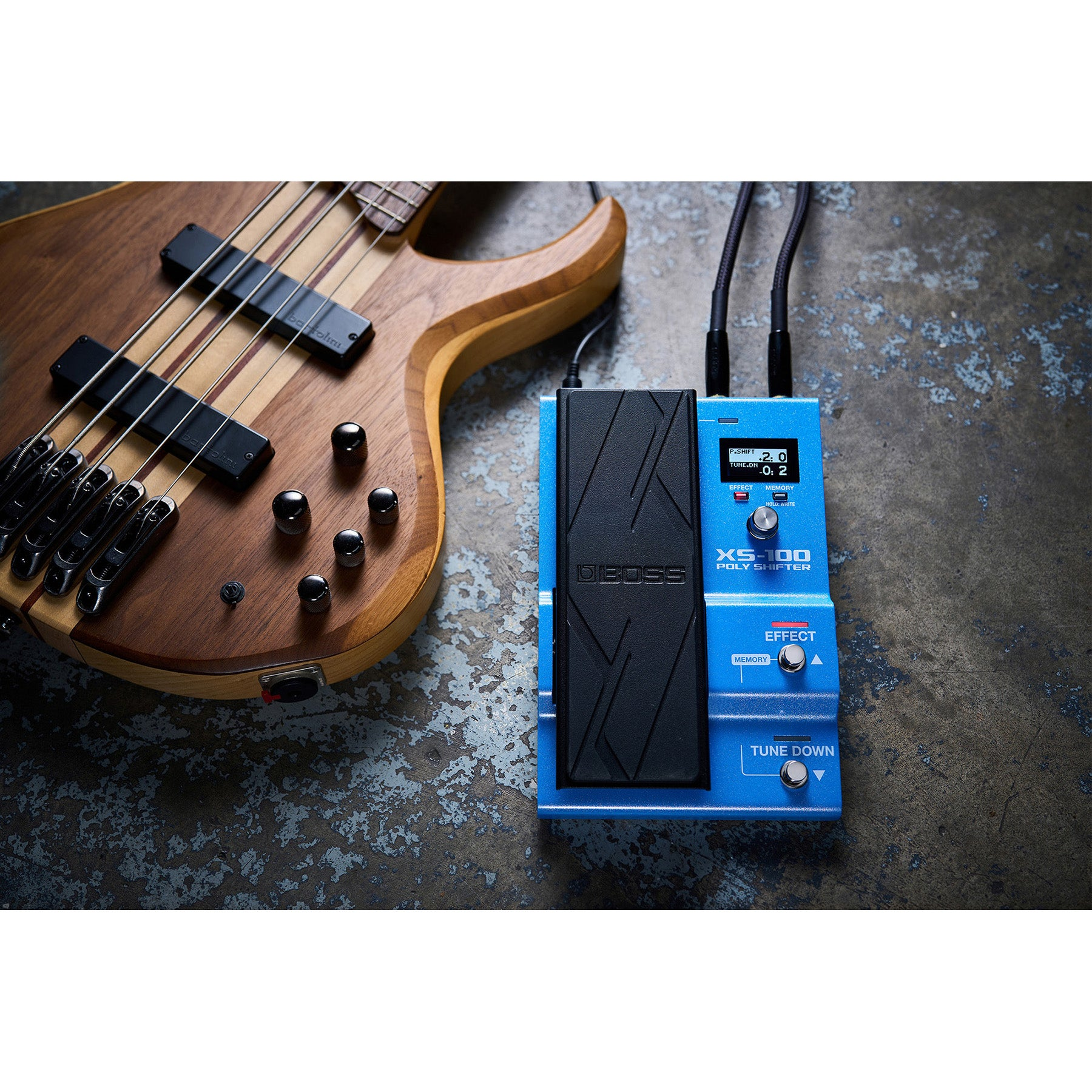 Een basgitaar en een blauw effectpedaal liggen op een getextureerd oppervlak.