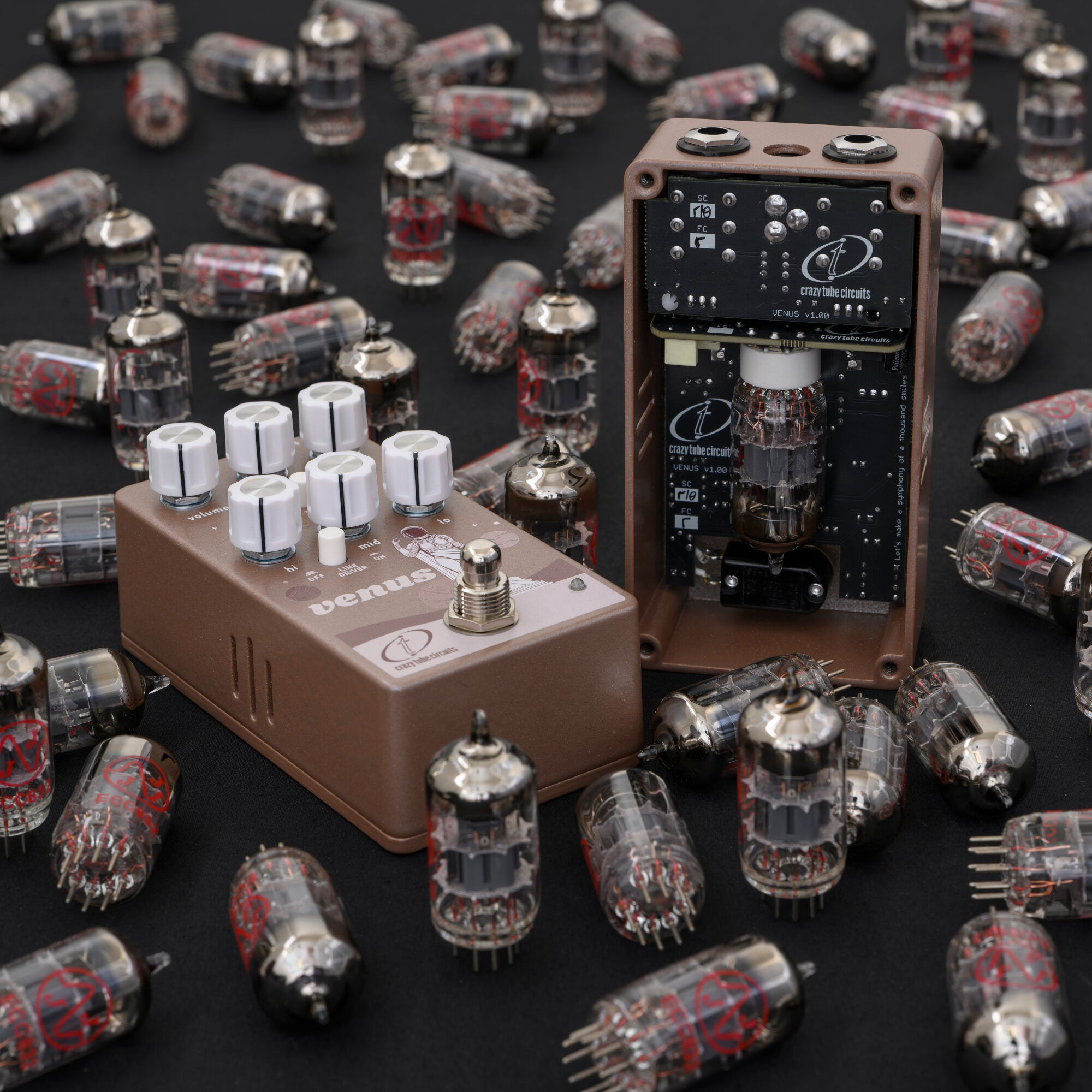 Brown effect pedal with white knobs, surrounded by vacuum tubes on a black background.