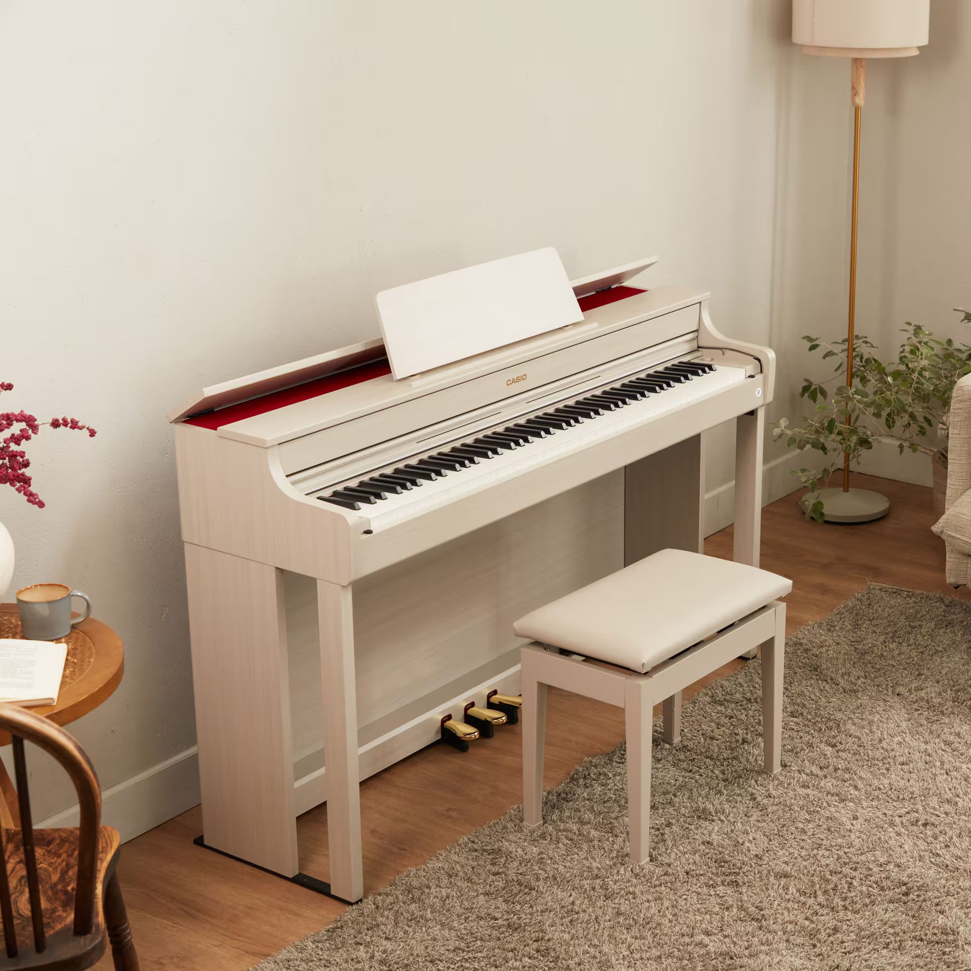 Un piano de couleur claire avec pupitre et tabouret sur un tapis.