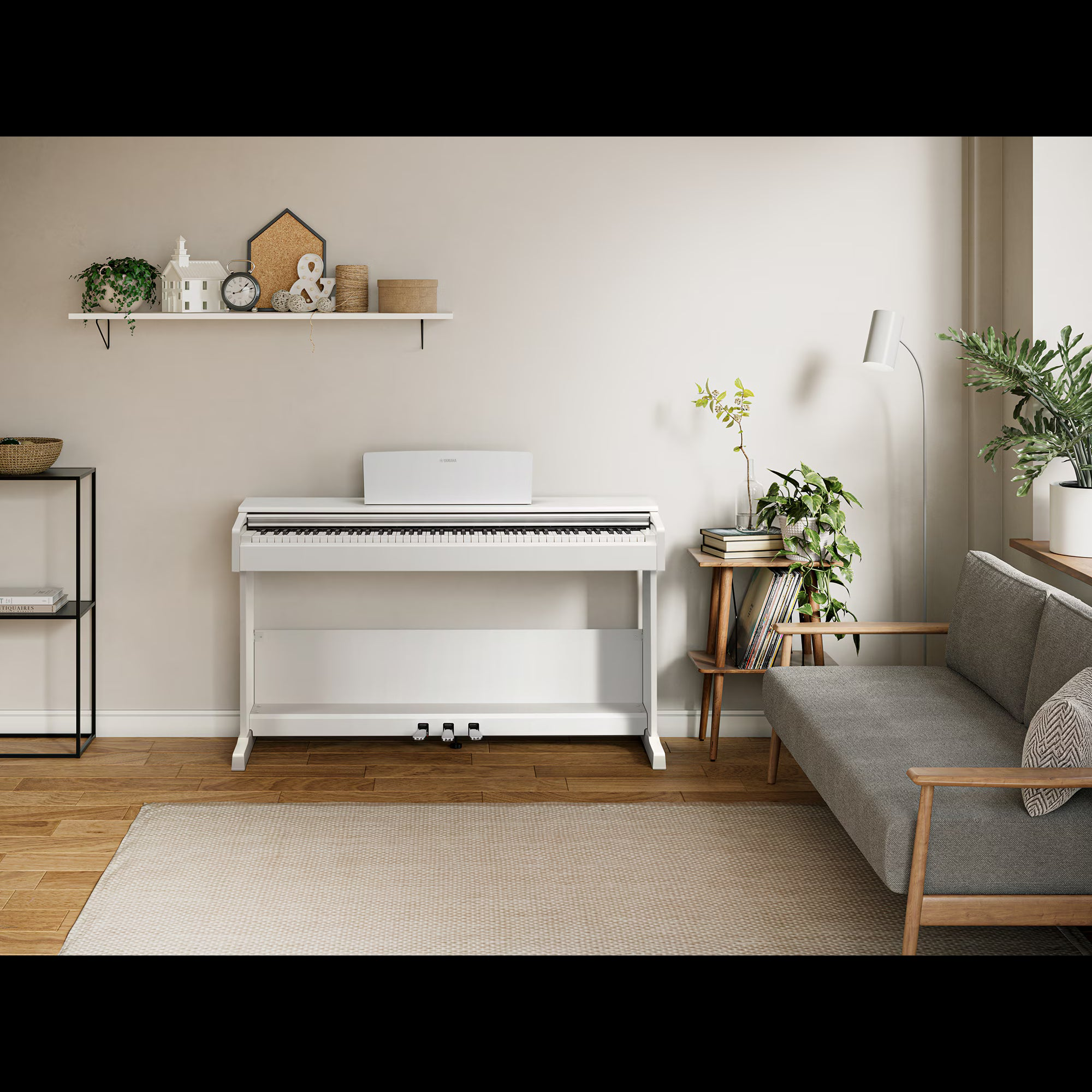 Een witte digitale piano staat op een houten vloer, voor een plank en een bank.