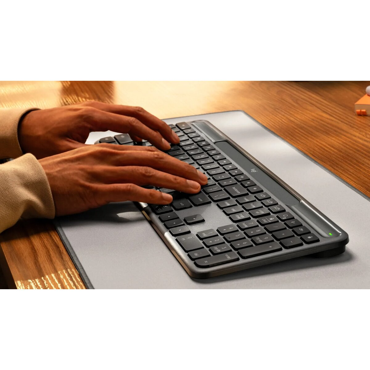 Mani che digitano su una tastiera scura su una scrivania.