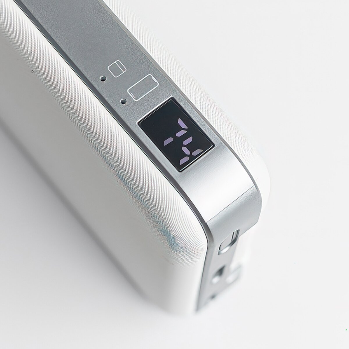 Un power bank bianco con accenti argentati e display digitale che mostra il 74%.