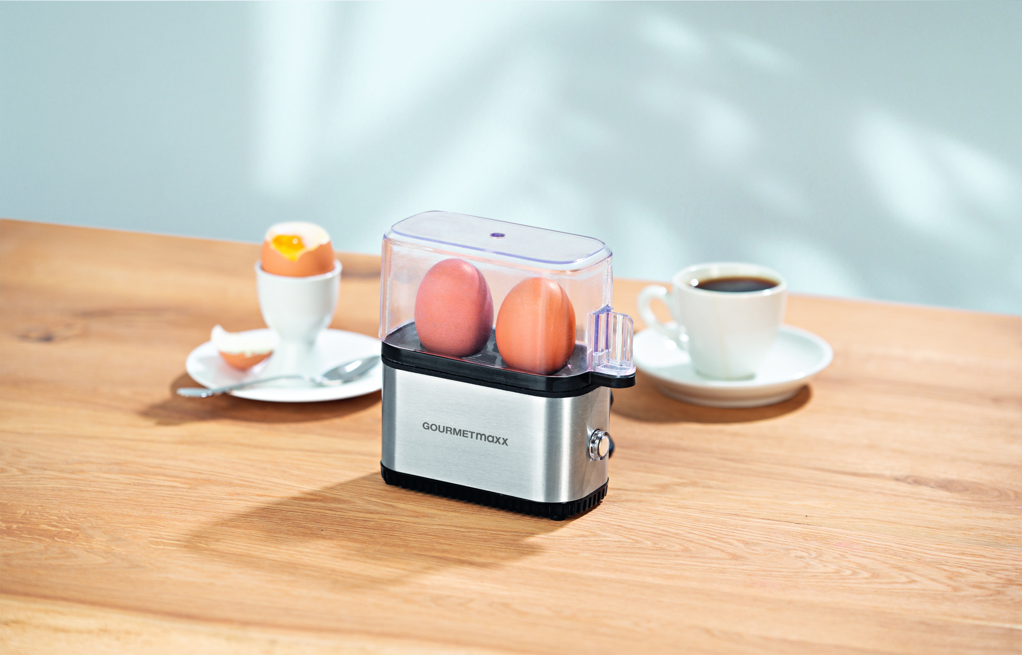 Urządzenie do gotowania jajek z dwoma jajkami, jajkiem na twardo i filiżanką kawy.