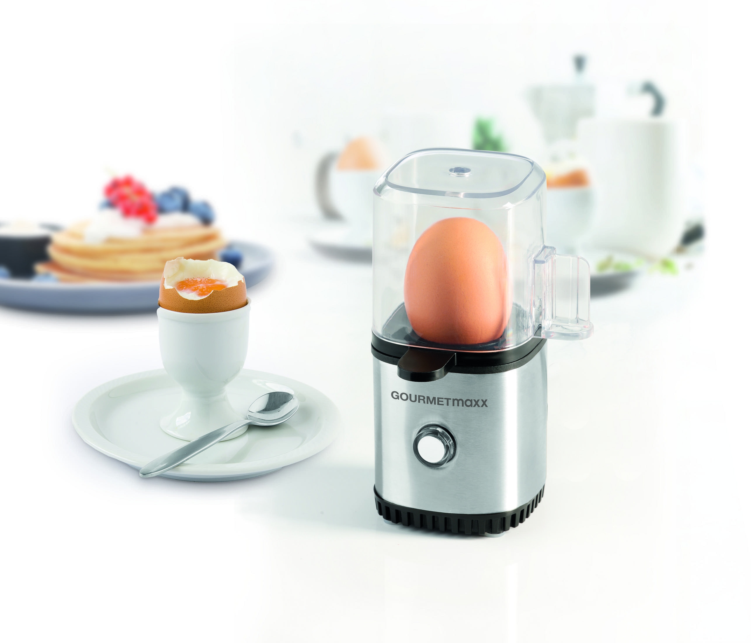 Jajko na miękko w kieliszku obok parowaru do jajek z jajkiem.