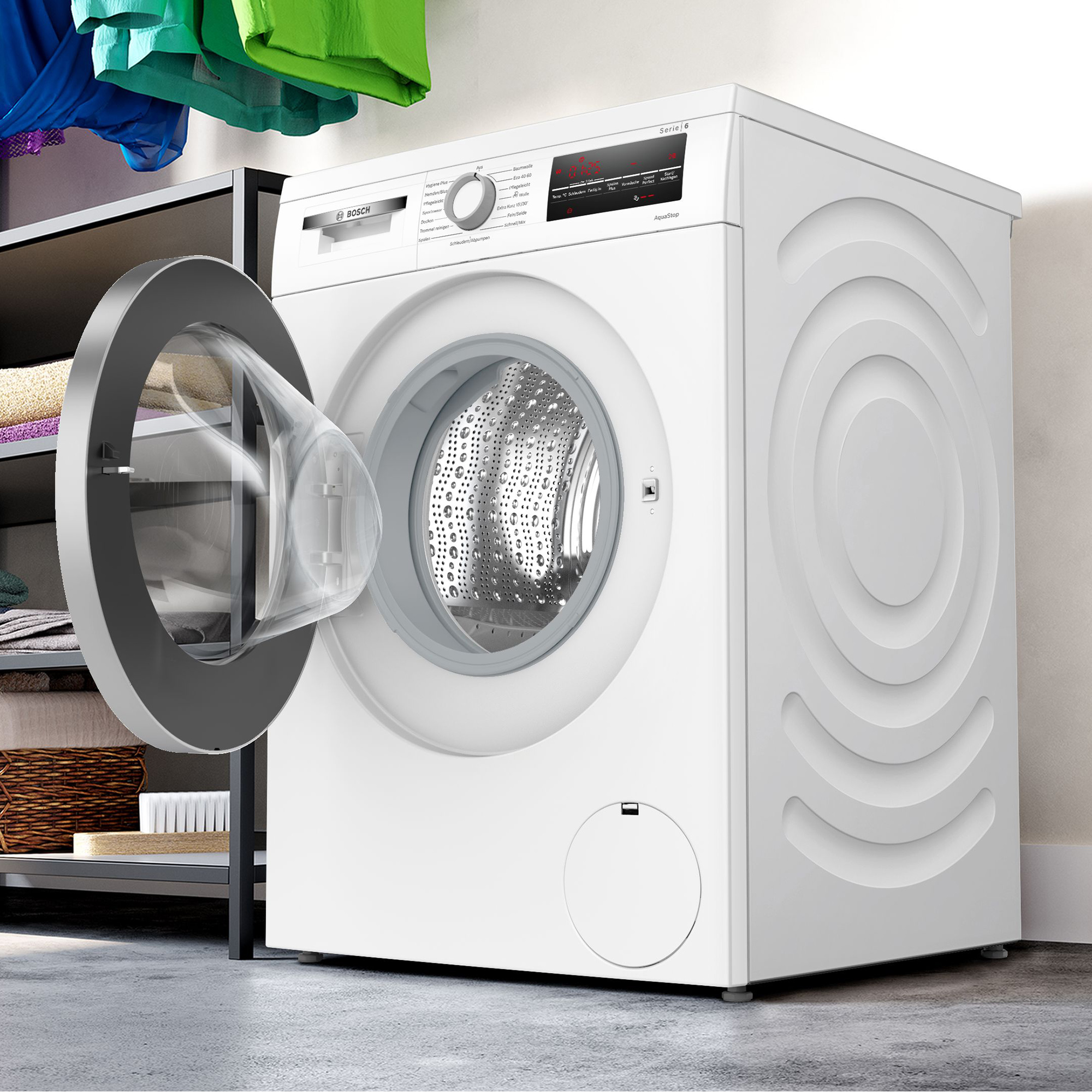 Eine weiße Bosch Waschmaschine mit geöffneter Tür steht neben einem Regal mit Wäsche.