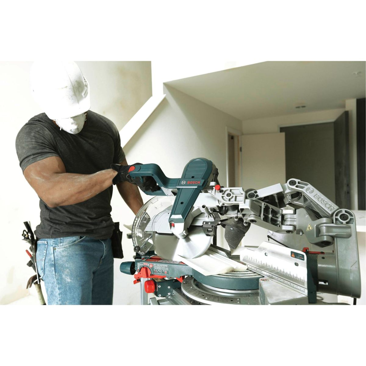 Mann in Helm und Maske bedient eine Bosch-Kapp- und Gehrungssäge mit Metallarm.