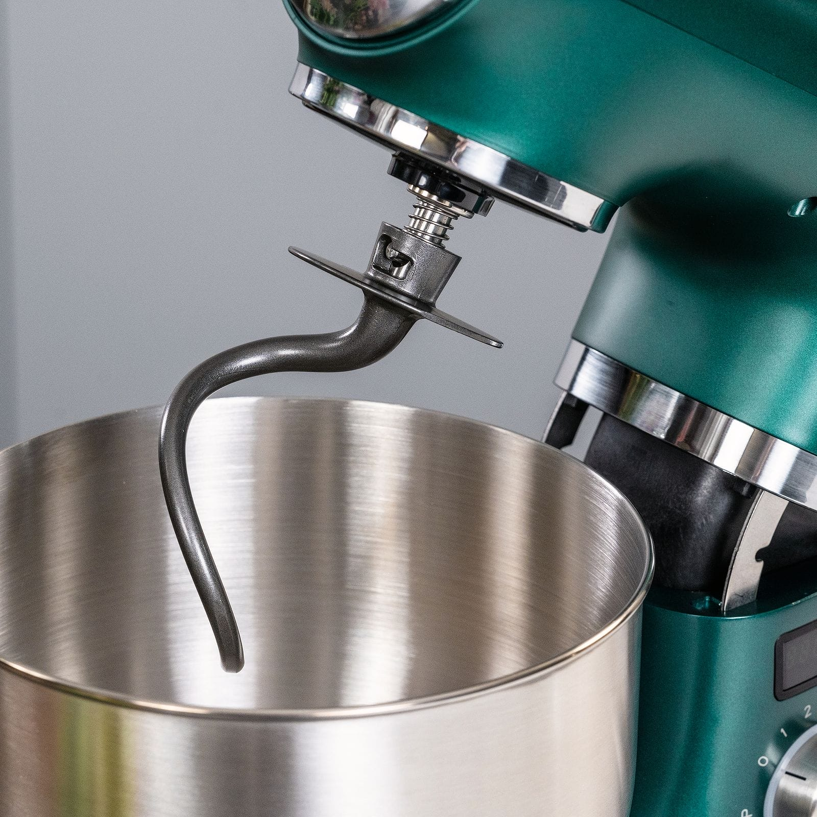 Ein grüner Küchenmixer mit einem Metall-Knethaken und einer Edelstahlschüssel.