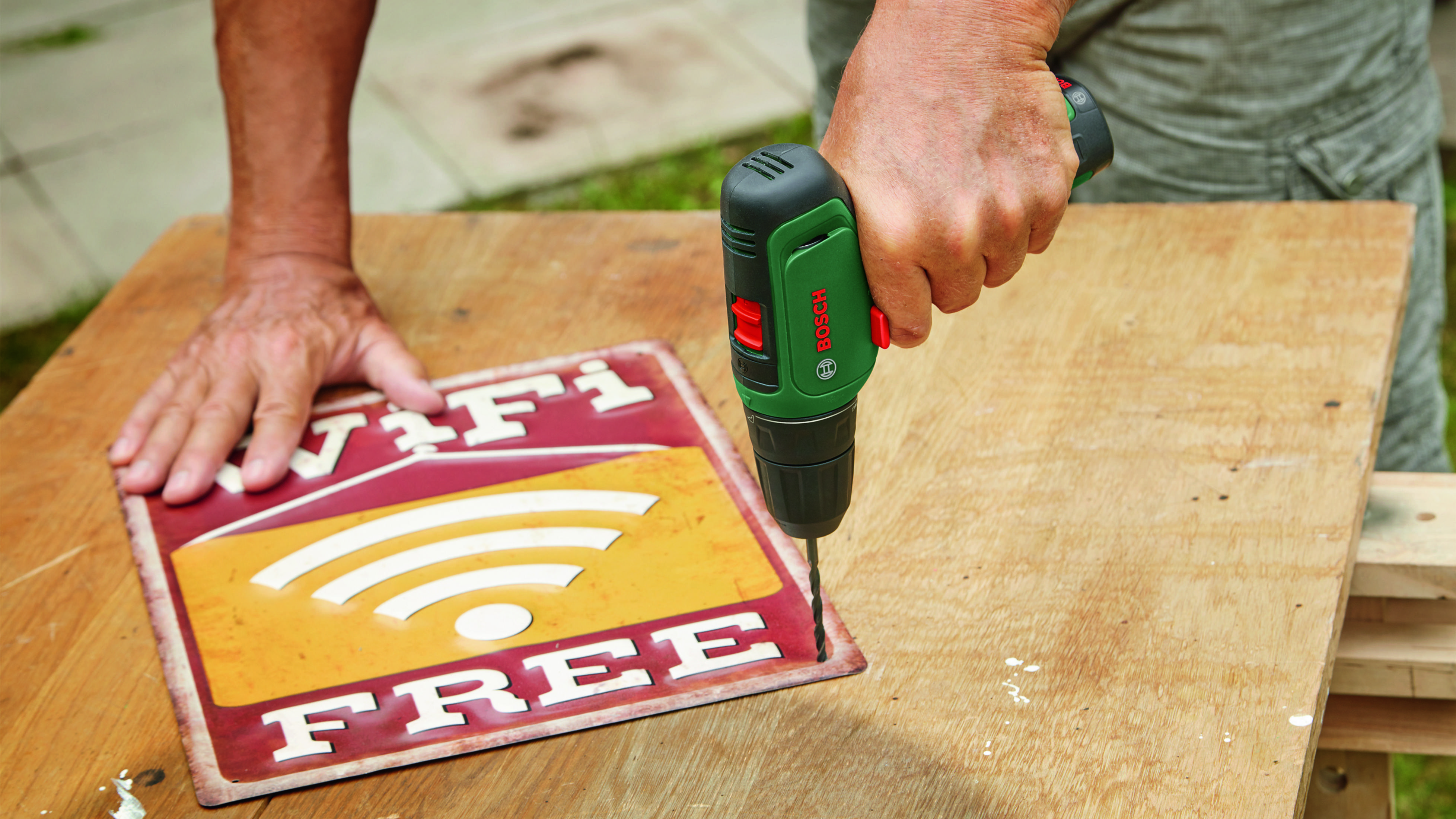 Mężczyzna wierci w czerwono-żółty znak "Darmowe Wifi".