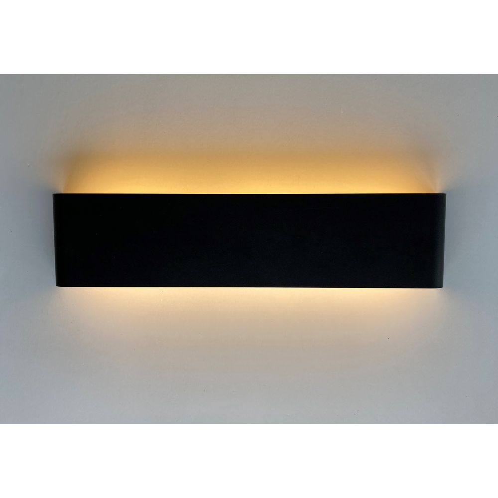 Schwarze Wandleuchte wirft warmes Licht nach oben und unten an eine weiße Wand.