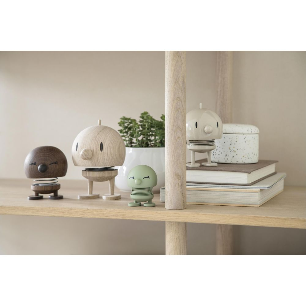 Quattro figure carine su uno scaffale: marrone, legno, verde e beige.