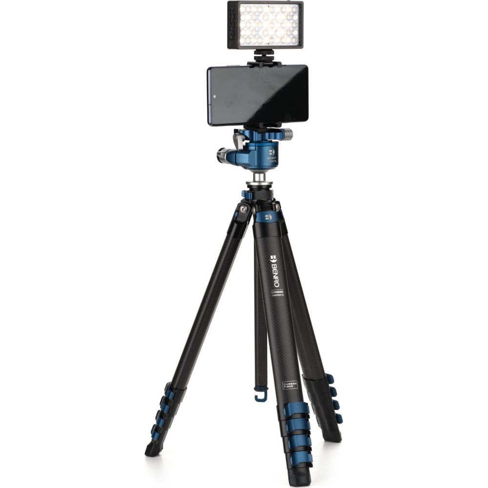 Un trépied noir en carbone avec tête bleue, téléphone et lumière.