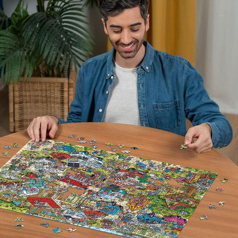 Uomo seduto a un tavolo di legno, che assembla un puzzle dettagliato con figure e veicoli.