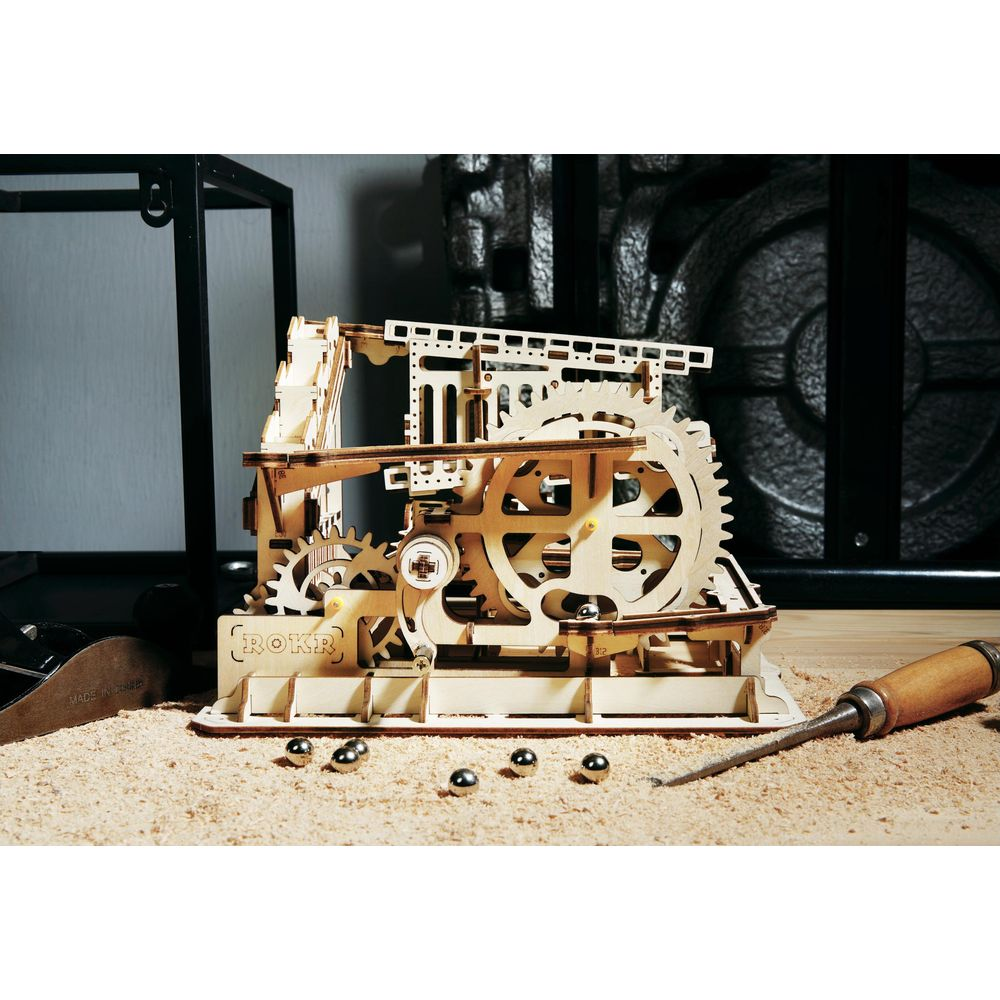 Ein detailliertes Holzmodell einer mechanischen Maschine mit Zahnrädern und Kugeln.