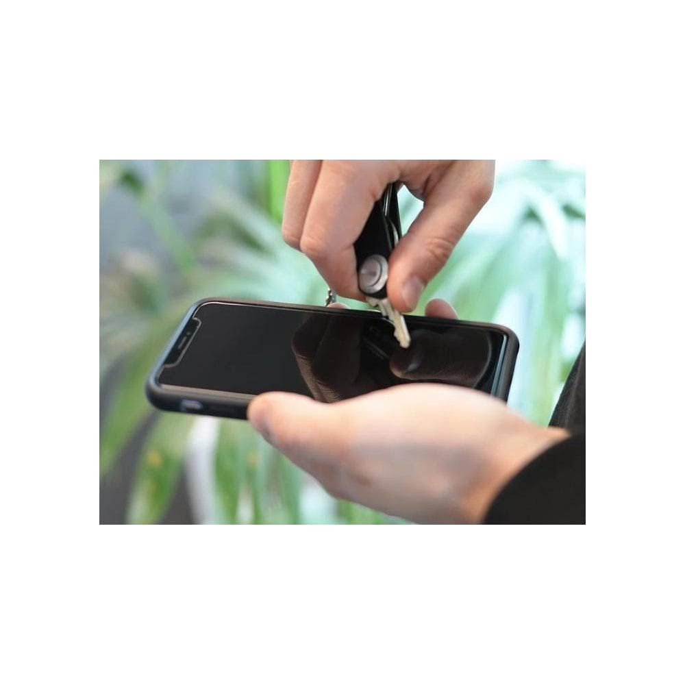 Eine Hand hält ein Smartphone, eine andere Hand lässt einen Schlüssel fallen.