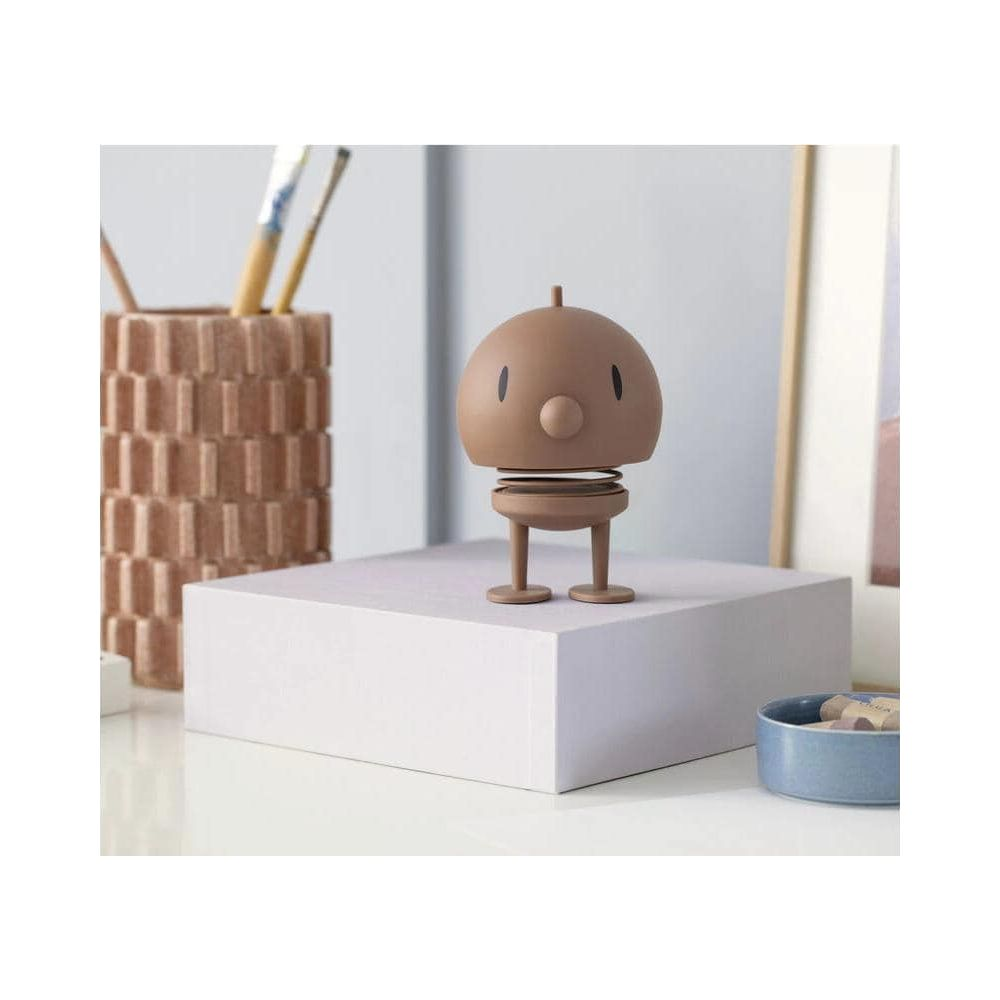 Una figura marrone a molla su un cubo bianco, accanto a un portaspazzole.