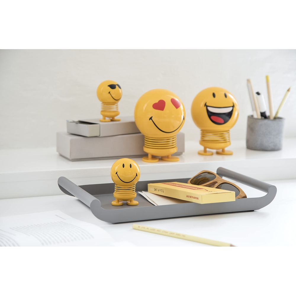 Vier gelbe Wackel-Smiley-Figuren auf einem Schreibtisch.