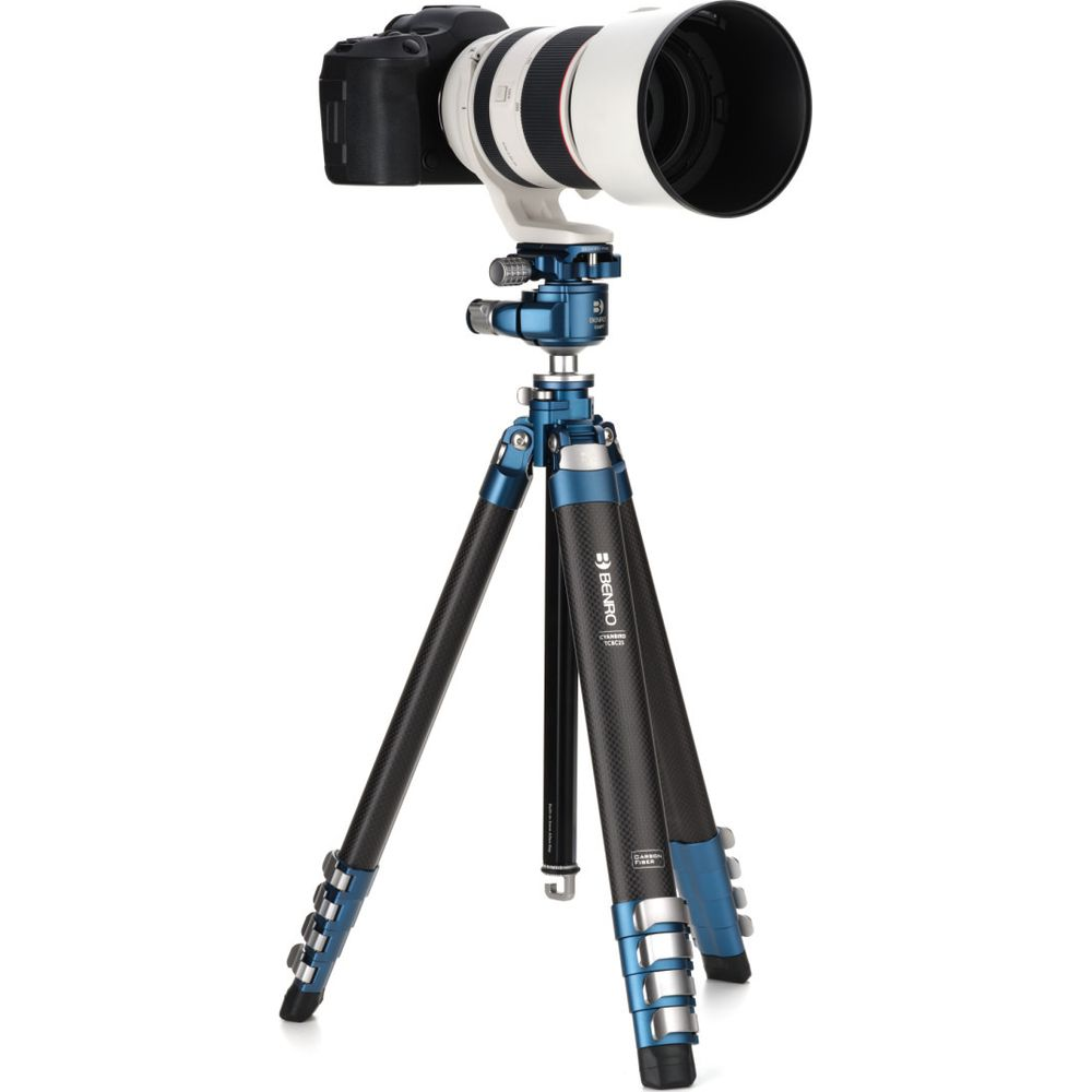 Un appareil photo numérique avec un téléobjectif est monté sur un trépied bleu en fibre de carbone.