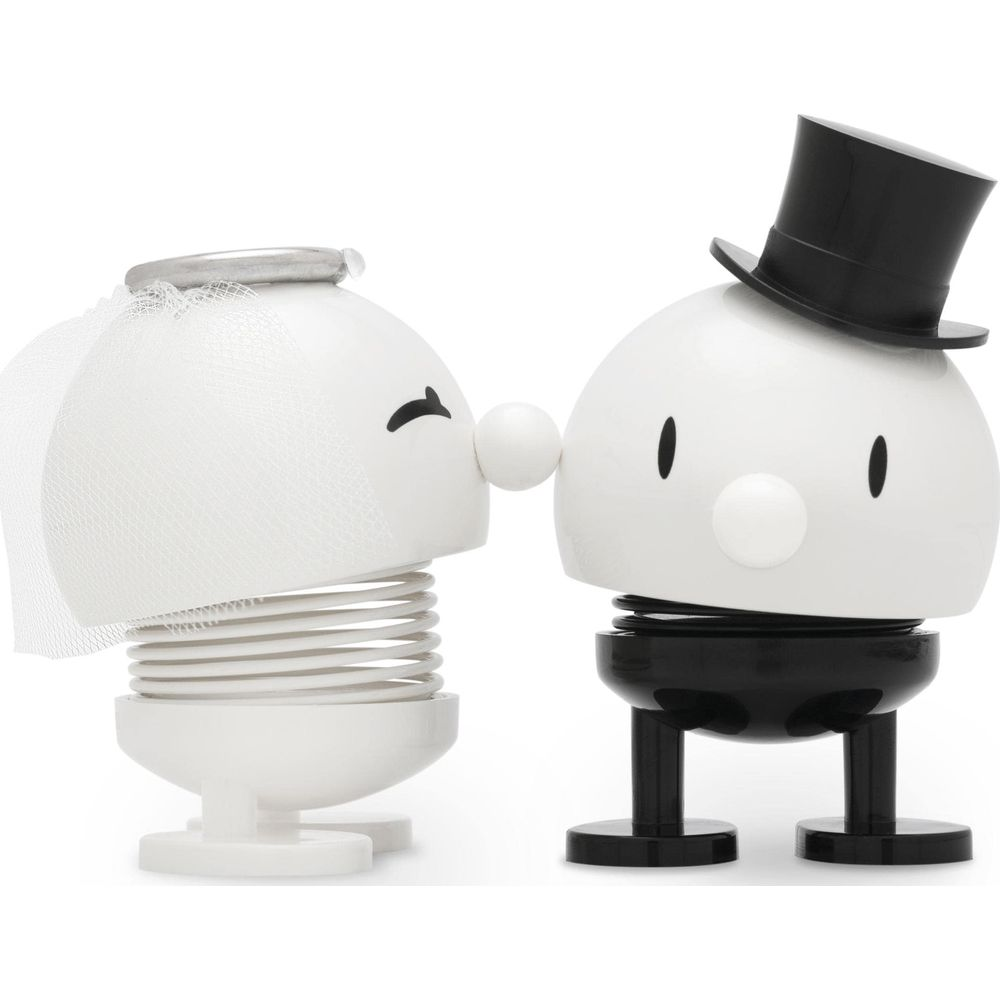 Due figure bianche, sposa e sposo, che si baciano.
