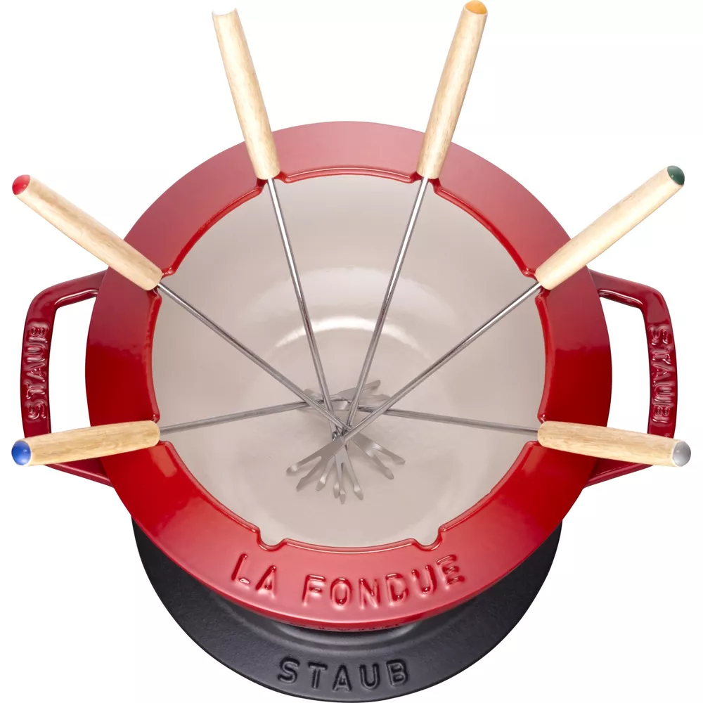 Ein rotes Fondue-Set mit sechs silbernen Gabeln mit Holzgriffen.