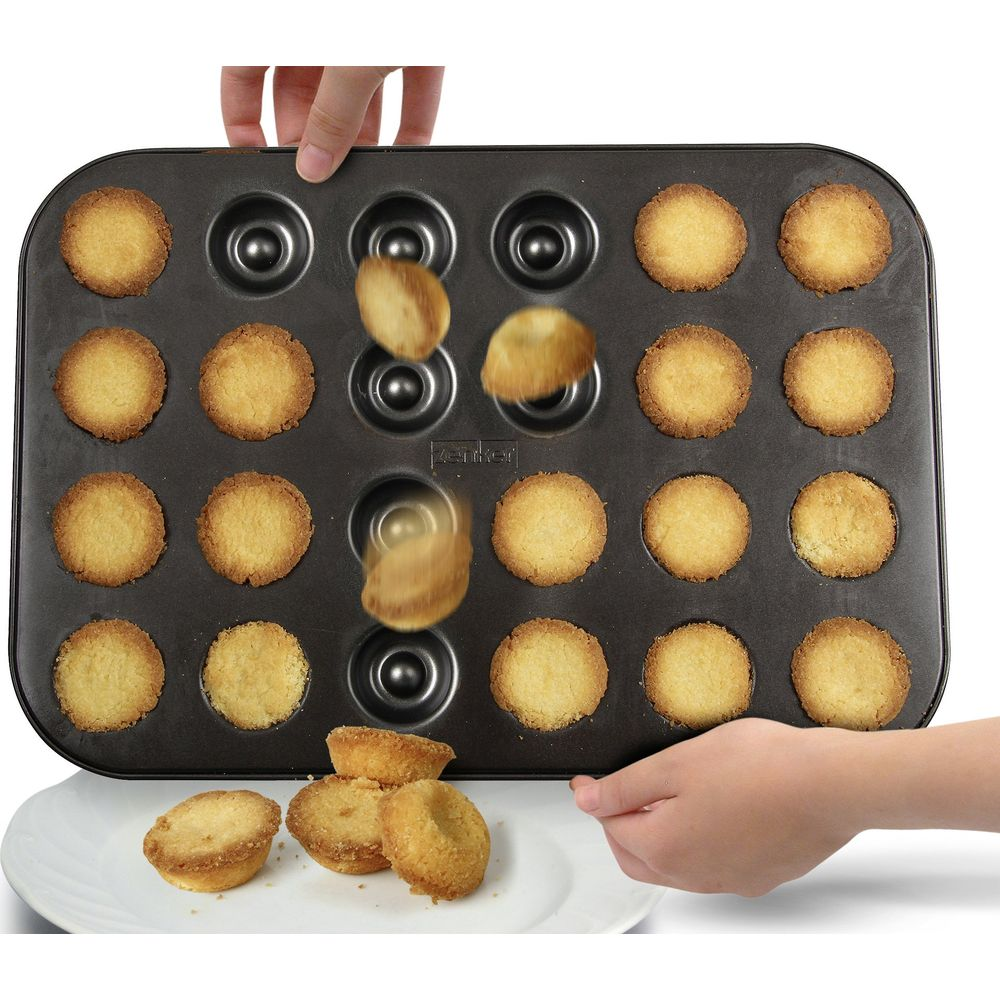 Ein Blech mit gebackenen Muffins, einige fallen heraus.