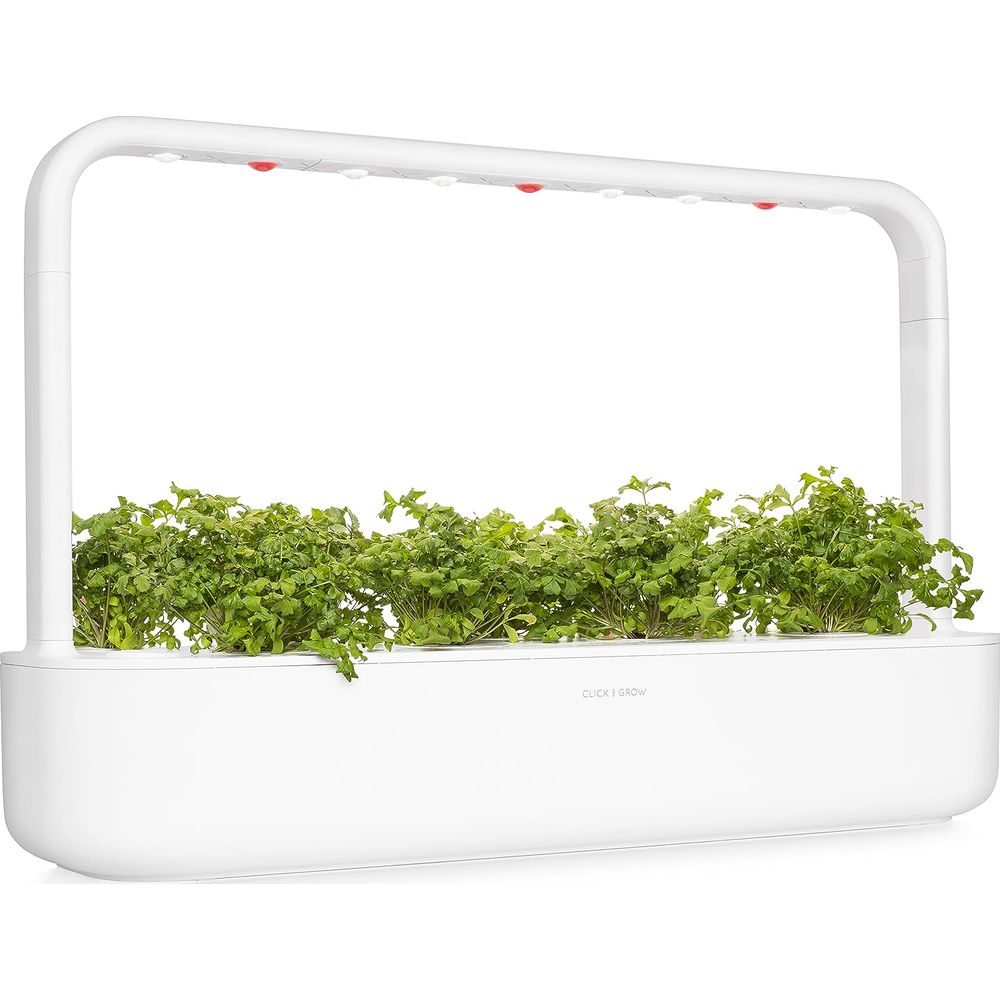 Weißer Indoor-Garten mit hellgrünen Sprossen unter einer gebogenen LED-Pflanzenlampe.