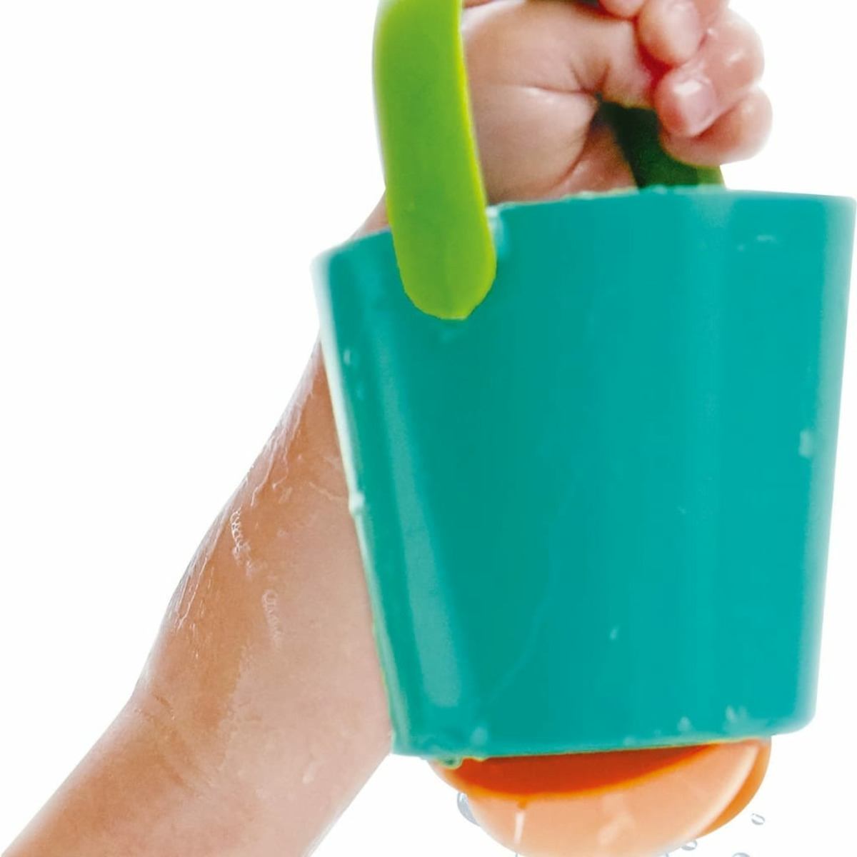 Un enfant tient un seau turquoise avec une poignée verte. L'eau s'écoule.
