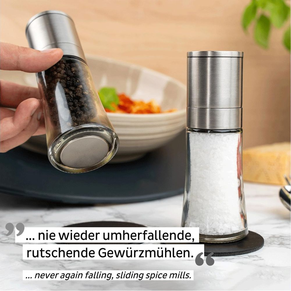 Eine Hand hält Pfeffermühle über Schüssel mit Essen. Salzstreuer daneben.