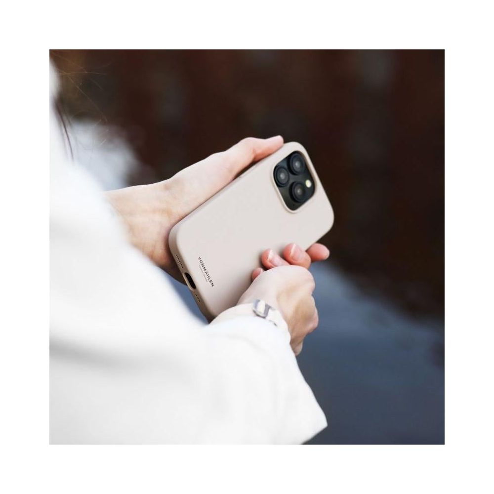 Eine Person hält ein hellbeiges Handy mit drei Kameras.
