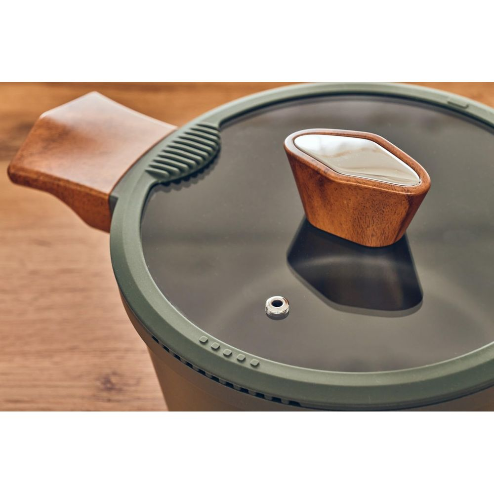 Ein Topf mit Holzgriff und Glasdeckel auf Holzhintergrund.