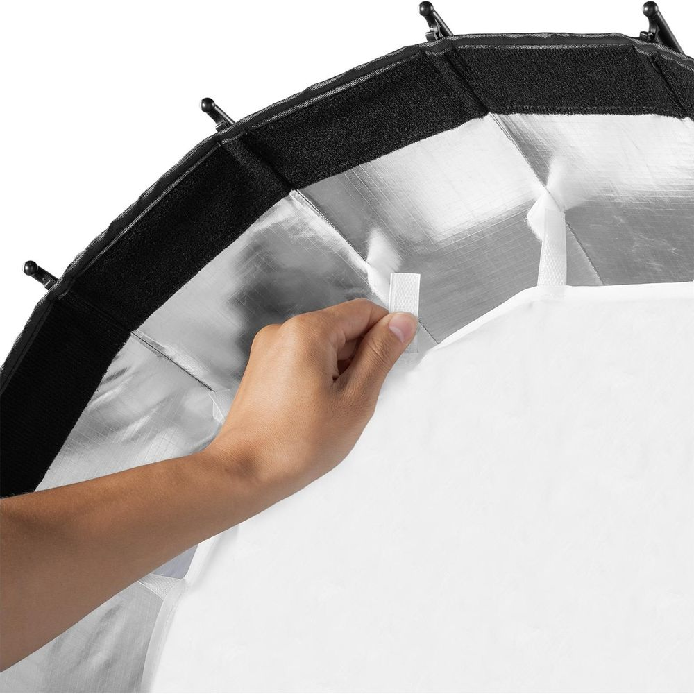 Une main attache un tissu blanc à un réflecteur argenté avec velcro.