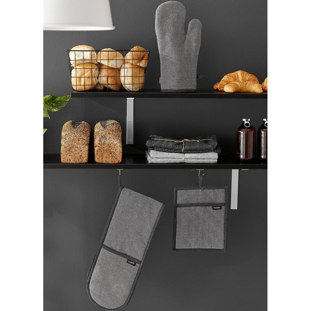 Une étagère présente du pain, des petits pains, un croissant, des maniques et des serviettes.