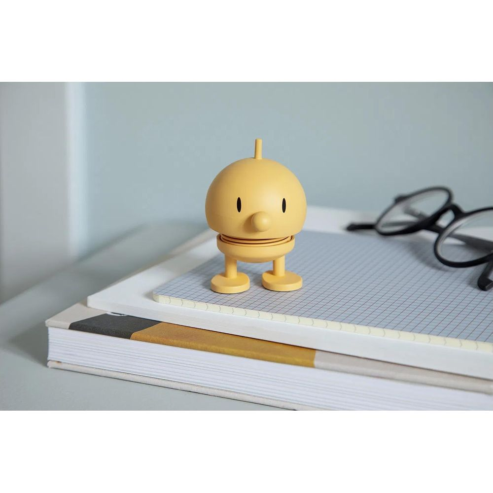 Un robot giocattolo giallo sta sui libri accanto a occhiali.