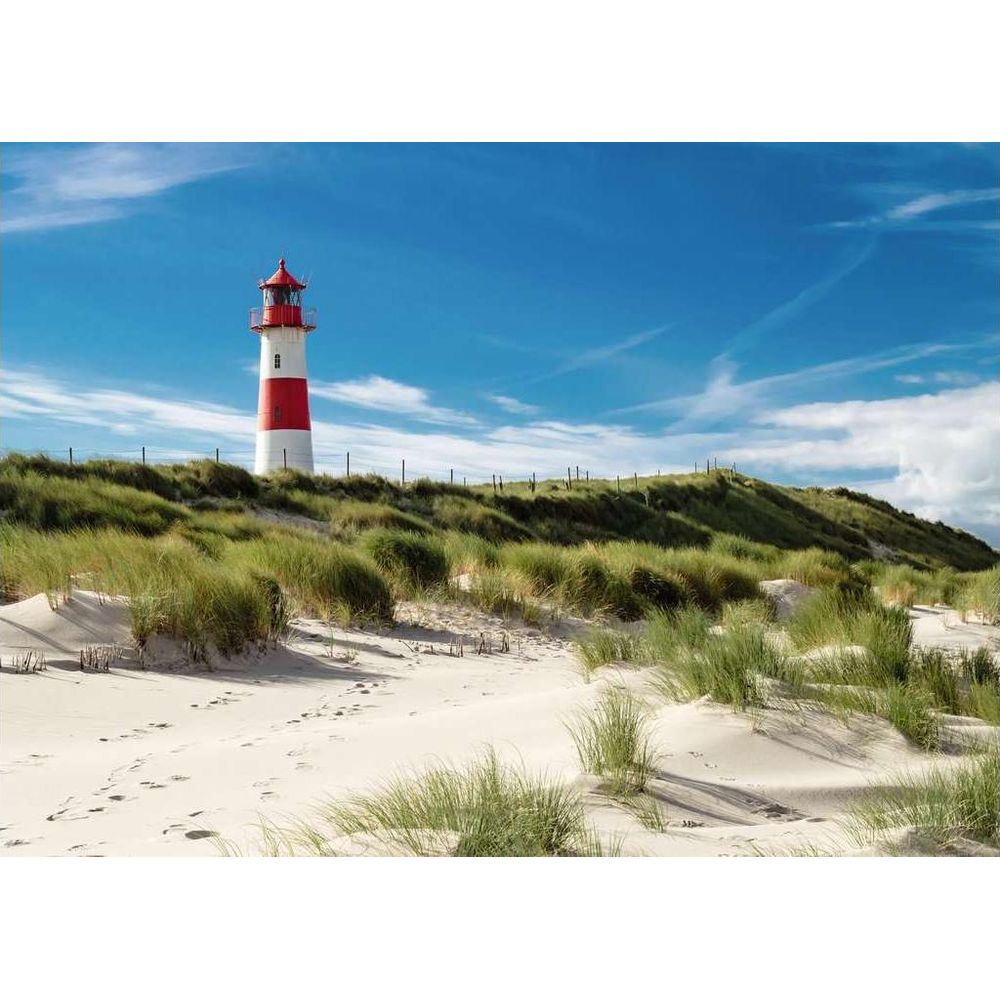 Ein rot-weißer Leuchtturm auf einer grasbewachsenen Düne unter blauem Himmel.