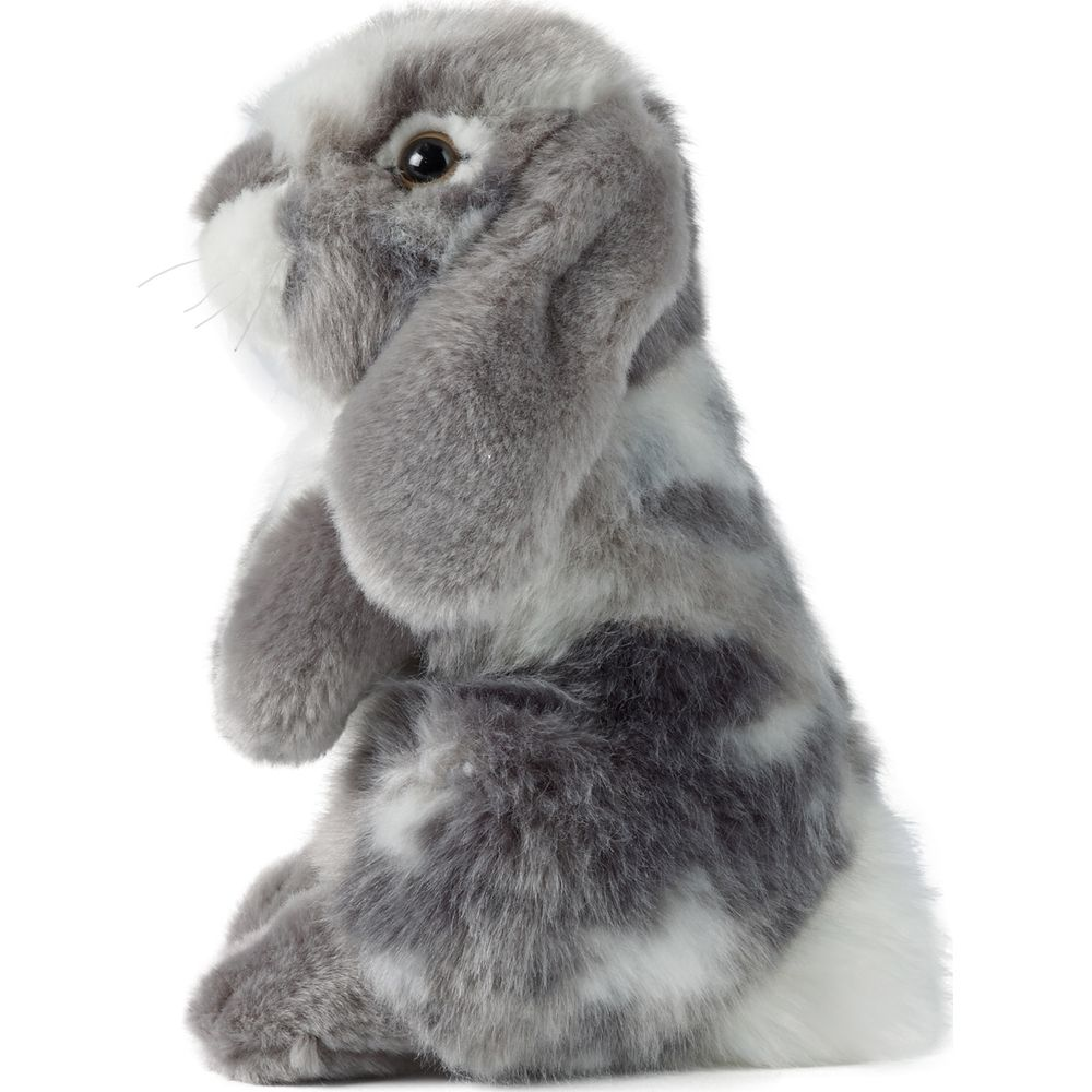 Un coniglietto di peluche soffice è seduto, maculato di grigio e bianco.