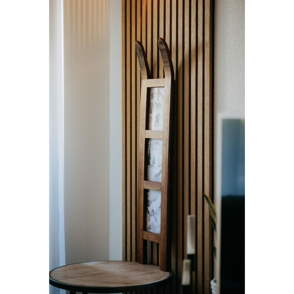 Cadre en bois avec trois photos en design de chaussure de ski contre un mur en bois.