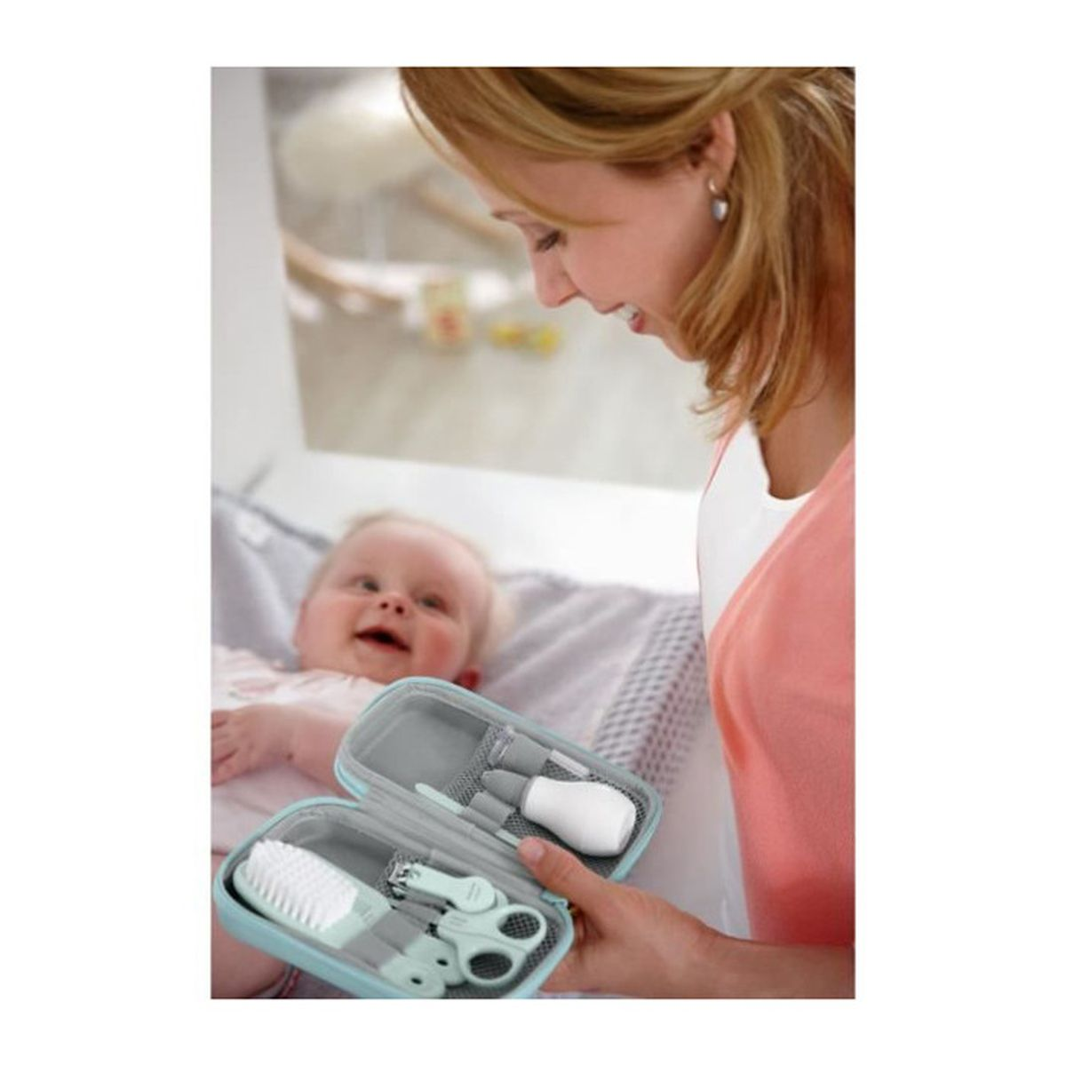 Frau hält Babypflegeset neben lächelndem Baby.
