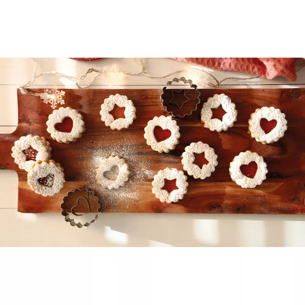 Biscotti Linzer con ripieno di marmellata su tagliere di legno, spolverati di zucchero a velo.