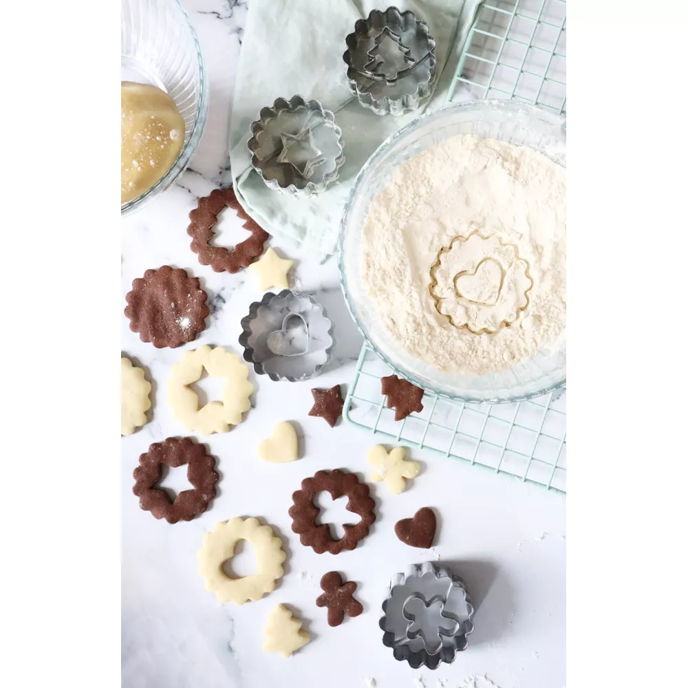 Biscotti e utensili da forno: impasto, farina, formine a stella, cuore, albero.