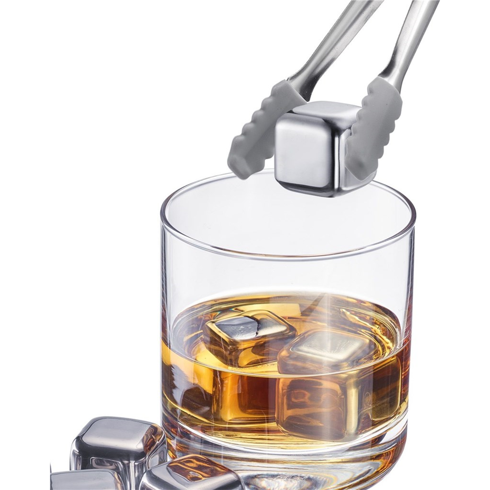 Edelstahl-Eiswürfel werden mit einer Zange in ein Whiskeyglas gegeben.