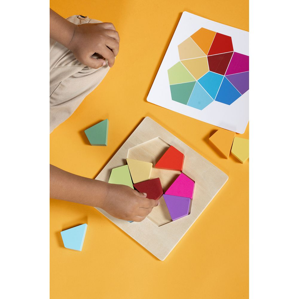 Un bambino gioca con un puzzle di legno colorato su sfondo arancione.