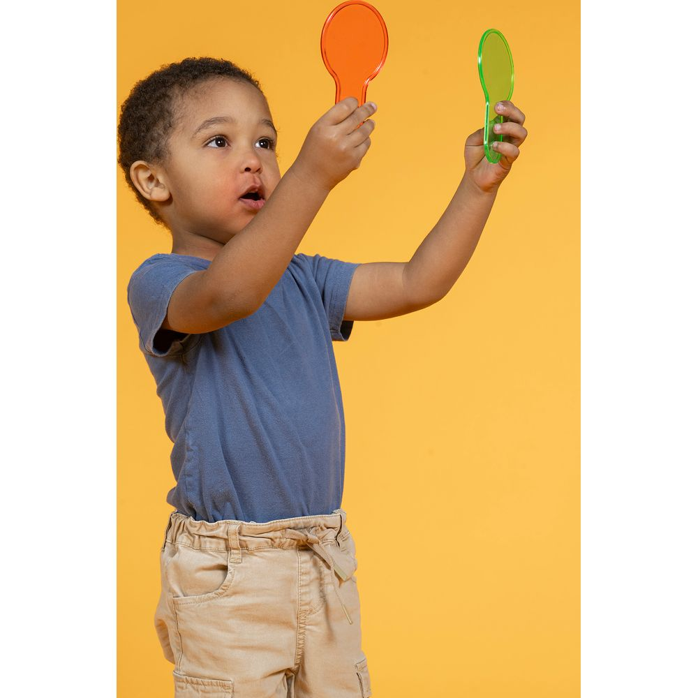 Un bambino tiene un filtro arancione e uno verde su sfondo giallo.