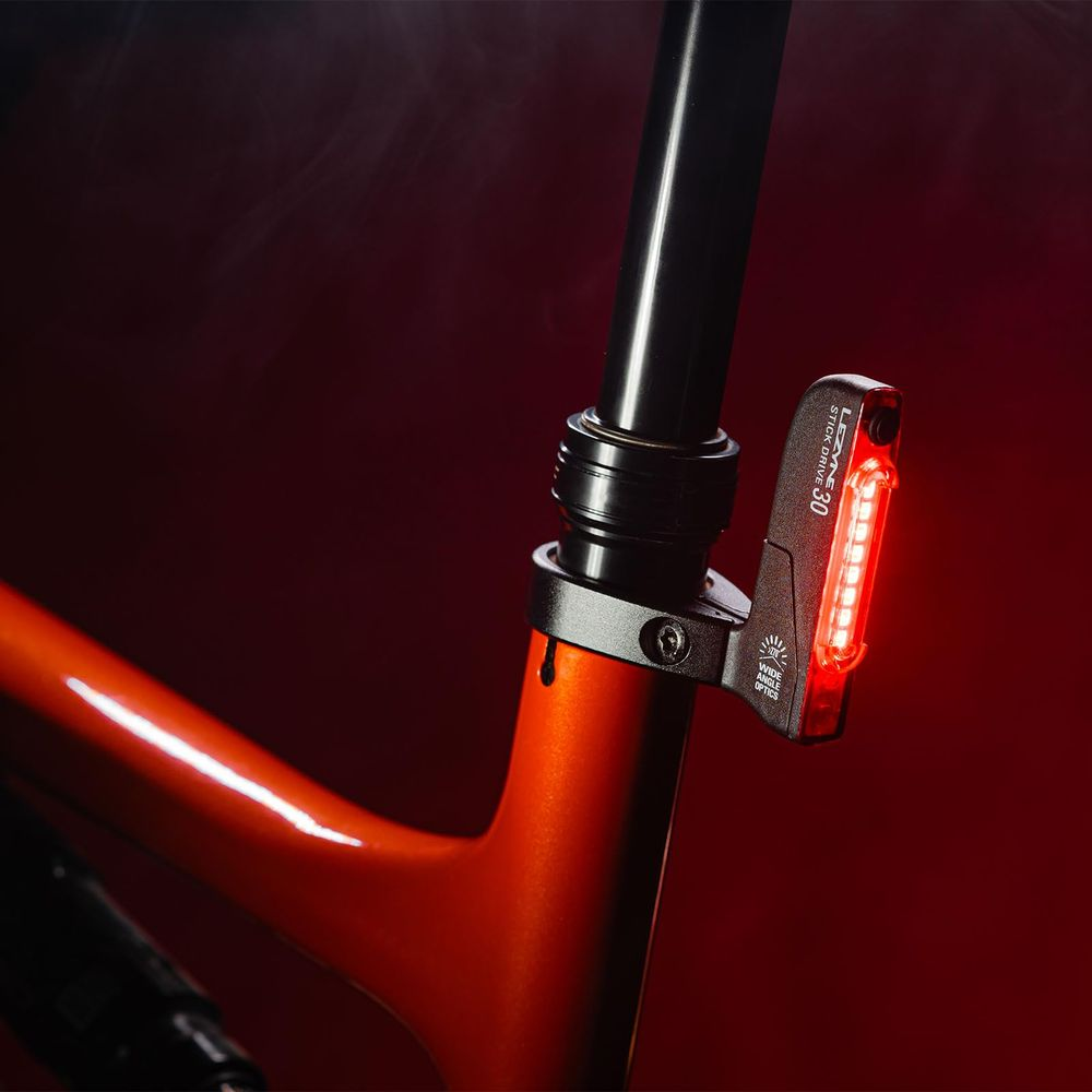 Ein rotes Rücklicht leuchtet auf dem Sitzrohr eines orangefarbenen Fahrradrahmens.