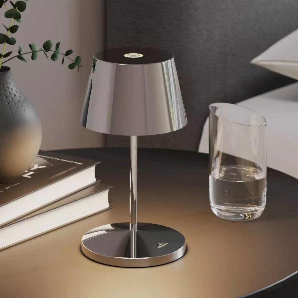 Una lampada da comodino lucida accanto a libri e un bicchiere d'acqua.