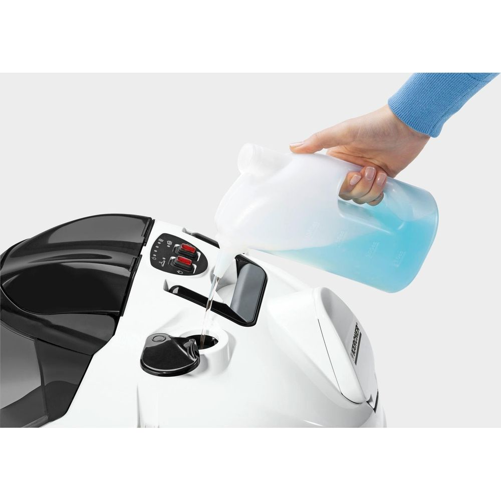 Eine Hand schüttet blaue Flüssigkeit aus einem Behälter in eine weiße Maschine.