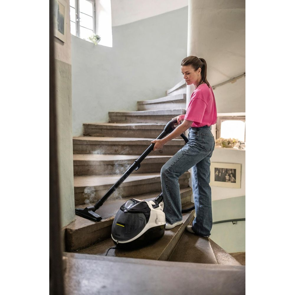 Eine Frau reinigt eine Steintreppe mit einem Dampfreiniger, der Dampf abgibt.