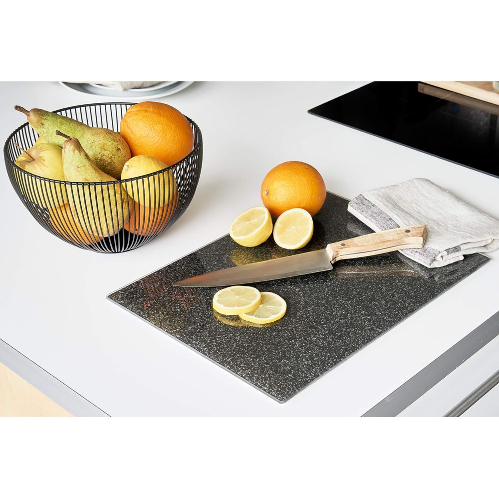 Obstschale mit Obst, Orangen, Zitronen und Messer auf einem Schneidebrett.