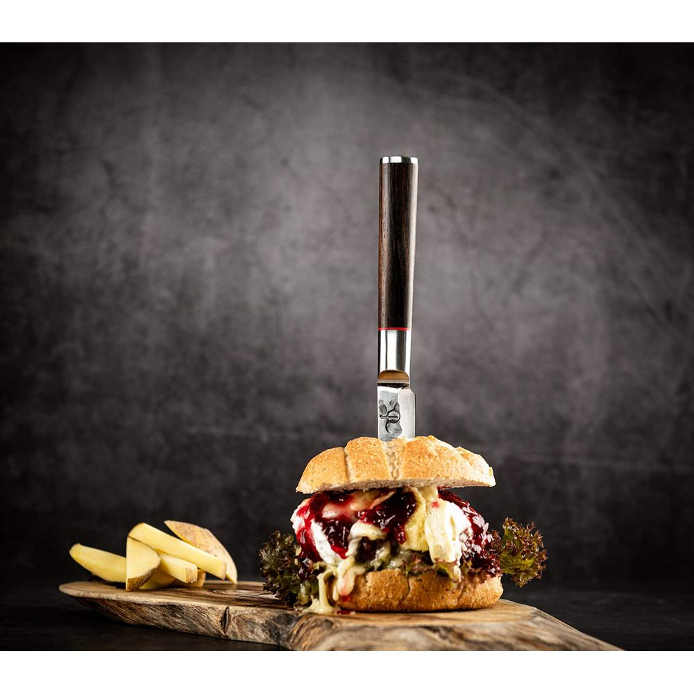 Ein Burger mit Messer, Pommes auf Holzbrett, dunkler Hintergrund.